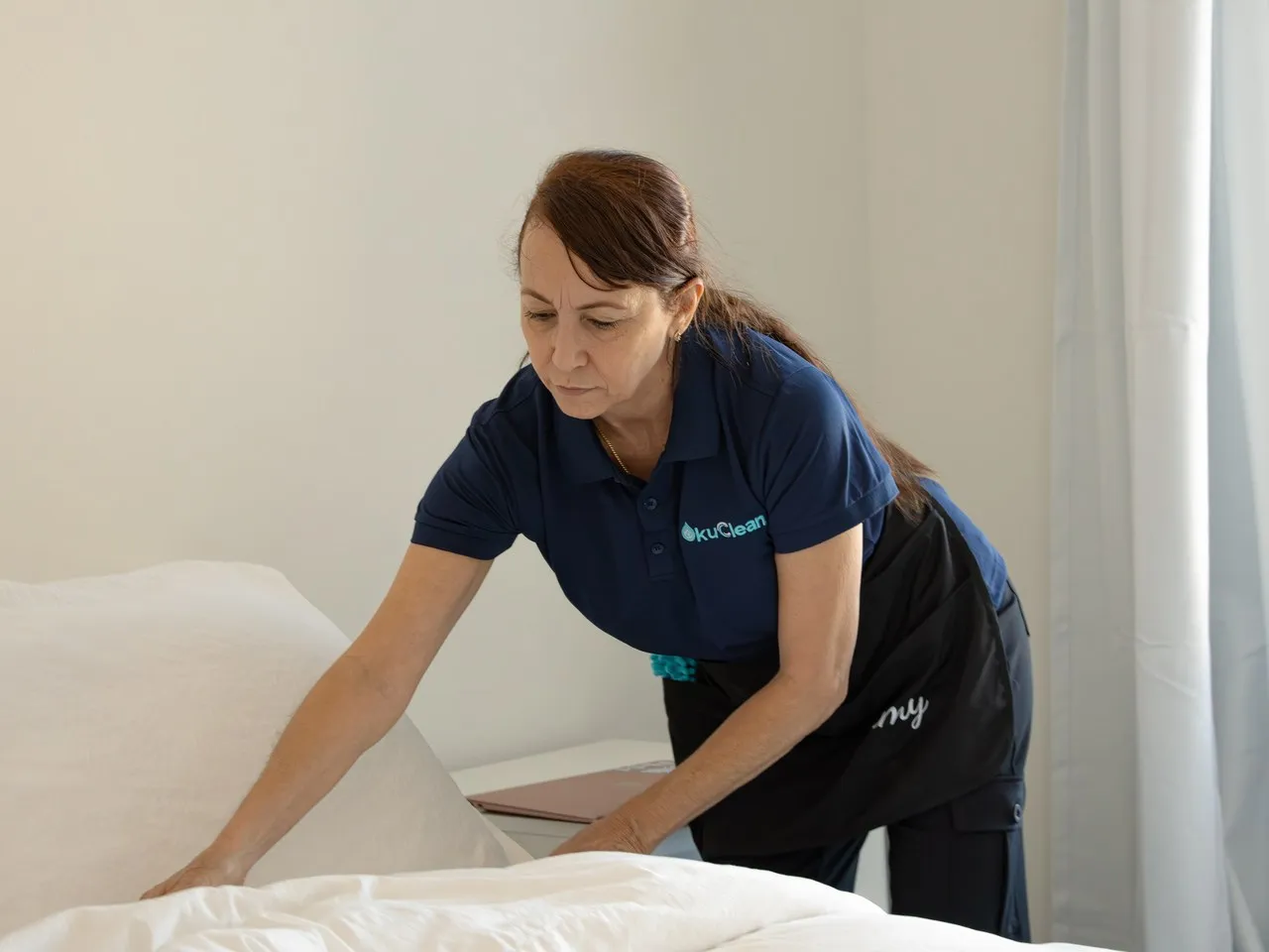 Yami, OkuClean Team Lead, making a bed with fresh white linens during a move-in cleaning in Las Vegas — turnover-ready service for property managers and rentals